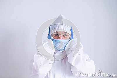 A woman in a protective suit and a medical mask covers her ears with her hands. I do not hear evil Stock Photo