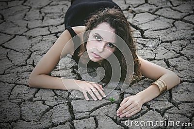 Woman protects a small sprout on a cracked desert soil Stock Photo