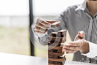 A woman is pulling a block of wood from a row and not breaking it down, like running a good business and solving problems. Stock Photo