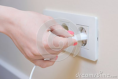 The woman pulls the electrical plug out of the socket wire Stock Photo