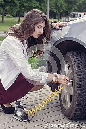 Woman pumps up her car tire Stock Photo