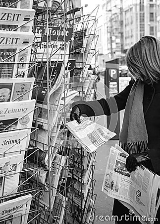 Woman purchases a Le Monde French Press newspaper from a newsstand Editorial Stock Photo