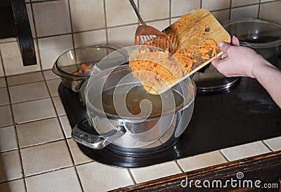 a woman puts grated carrots in a pan, ingredients for cooking borsch soup Stock Photo