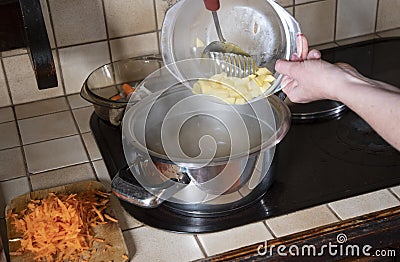 a woman puts potatoes in a pot in the kitchen, ingredients borsch soup Stock Photo