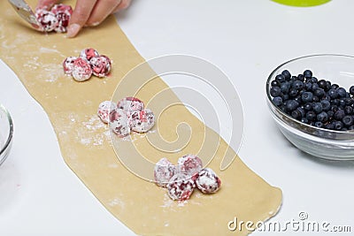 A woman puts starchy cherries on the rolled dough. Cooking dumplings Stock Photo