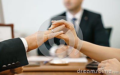 Woman puts a wedding ring in a registry office for a man. Marriage and hands close-up against the background of the ceremony maste Stock Photo