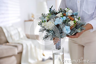 Woman putting beautiful wedding winter bouquet in vase at home, closeup. Space for text Stock Photo