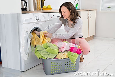 Woman Putting Clothes Into Washing Machine Stock Photo