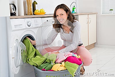 Woman Putting Clothes Into Washing Machine Stock Photo