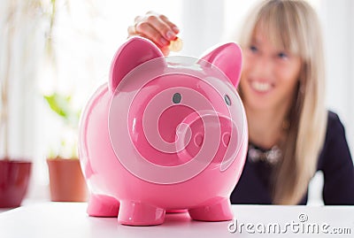 Woman putting coin in piggy bank Stock Photo