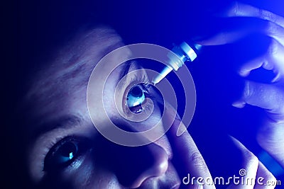 Woman is putting drops in his eyes. Medical treatment concept. Allergic conjunctivitis problem..Works on internet in front of Stock Photo