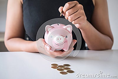 Woman putting golden coin in pink piggy bank for step up growing business to profit and saving with piggy bank, Saving money for Stock Photo