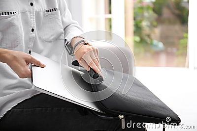 Woman putting laptop into case indoors Stock Photo