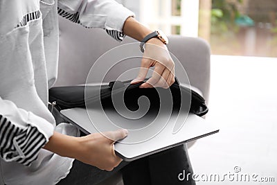 Woman putting laptop into case indoors Stock Photo