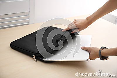 Woman putting laptop into case at table Stock Photo