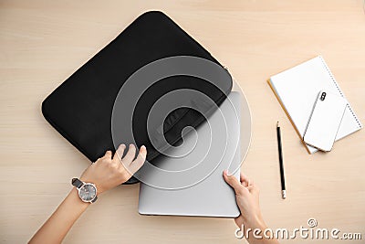 Woman putting laptop into case at table Stock Photo