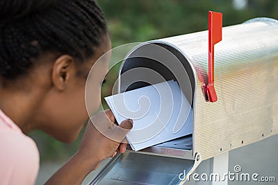 Woman Putting Letter In Mailbox Stock Photo