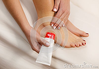 Woman putting ointment on bad ankle applying cream Stock Photo