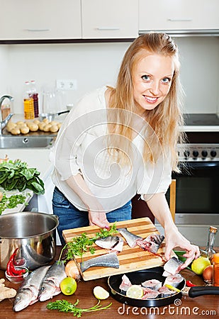 Woman putting pieces of fish into fryingpan Stock Photo