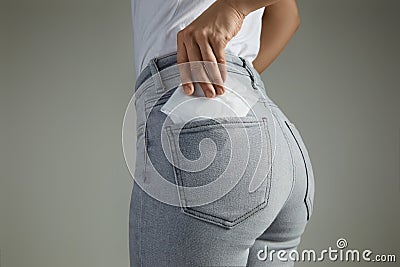 Woman putting sanitary pad into jeans pocket Stock Photo