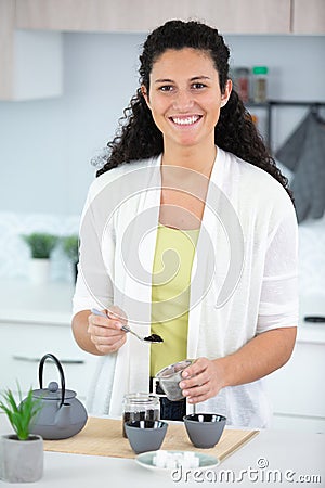woman putting tea spoon ground coffee in moka pot Stock Photo
