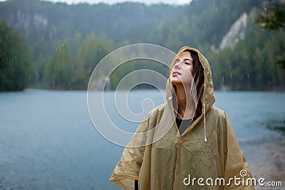 Woman in raincoat near lake in rainy day. Stock Photo