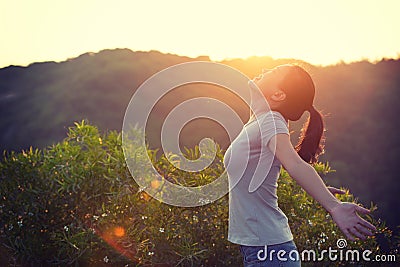 woman raised arms to sunrise on mountain top in the moring Stock Photo