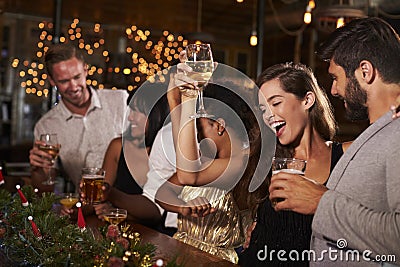 Woman raising a glass at a Christmas party in a bar Stock Photo