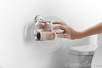 Woman reaching for empty toilet paper roll in bathroom, closeup Stock Photo