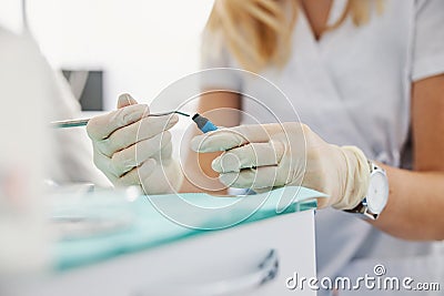 Woman reaching inside composite material bottle with dental carver Stock Photo