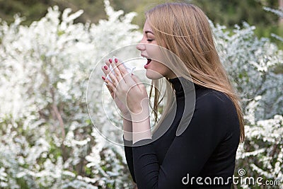 Woman with hay fever in front of white flowers Stock Photo
