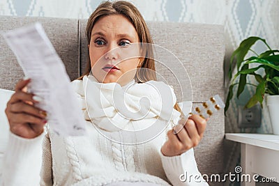 Woman read medicine leaflet before taking pills lying in bed. Careful female checking medication instructions for safe Stock Photo