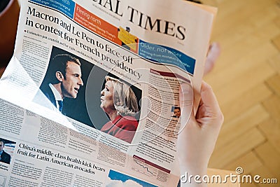 Woman reading Financial Times with Emmanuel Macron and Marine L Editorial Stock Photo