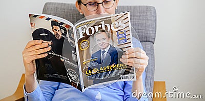 Woman reading Forbes France billionaires list Editorial Stock Photo