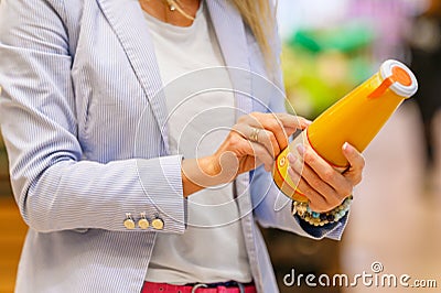 Woman reading ingredients and nutrition information on juice bottle Stock Photo