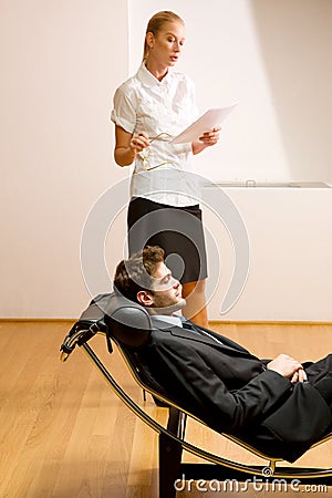 Woman reading man lying on chaise longue Stock Photo