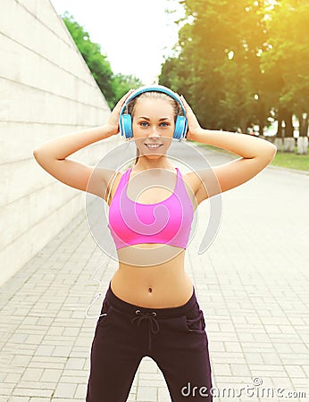 Woman ready to workout in city, female athlete with headphones listens to music, sport and healthy lifestyle Stock Photo