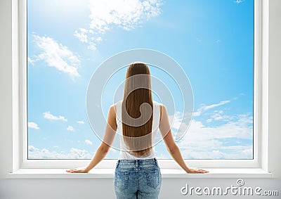 Woman Rear View looking at Window. Young Girl Back Side Silhouette look forward and thinking. Morning wake up Woman. Sky Stock Photo