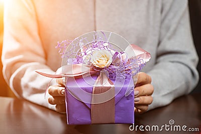 Woman received beautiful purple gift box with present in rays of Stock Photo