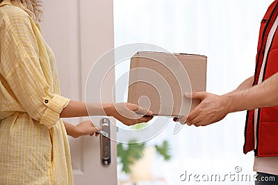 Woman receiving parcel from deliveryman on blurred background, closeup Stock Photo