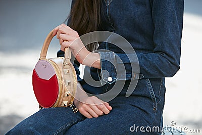 Woman with red and beige Salar leather bag and blue jeans overalls before Blumarine fashion show, Milan Editorial Stock Photo