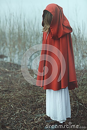 Woman with red cloak in misty desolated land Stock Photo