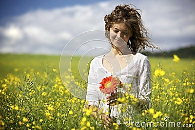 Woman with red flowers in rapeseed field. Stock Photo