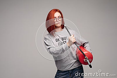 A woman with red hair in the Studio holding a fire extinguisher. An emotional bright woman extinguishes everything with Stock Photo