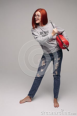 A woman with red hair in the Studio holding a fire extinguisher. An emotional bright woman extinguishes everything with Stock Photo