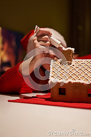 Woman in red hat building gingerbread house. Stock Photo