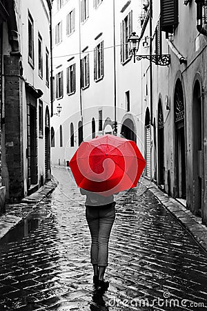 Woman with red umbrella on retro street in the old town. Wind and rain Stock Photo