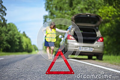 Woman in reflective vest near broken car Stock Photo