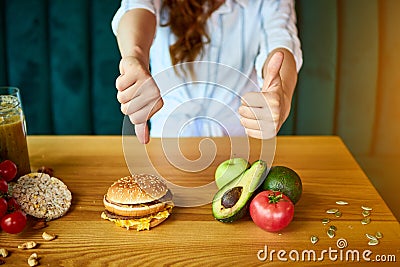 Woman is refusing to eat unhealthy hamburger. Cheap junk food vs healthy diet Stock Photo