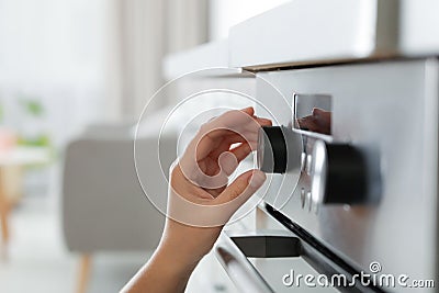 Woman regulating cooking mode on oven pane Stock Photo